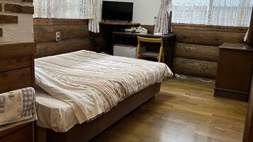 Ein Schlafzimmer mit Bett, Schreibtisch, Fernseher und Klimaanlage.