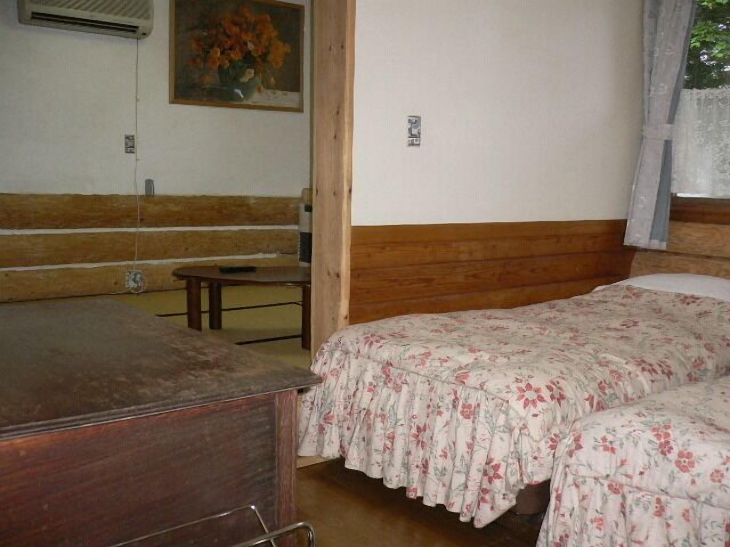 A room with a wooden bench, a bed with floral bedding, and a painting on the wall.