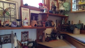A room with wooden shelves displaying various items like pottery, a sewing machine, and a fan.