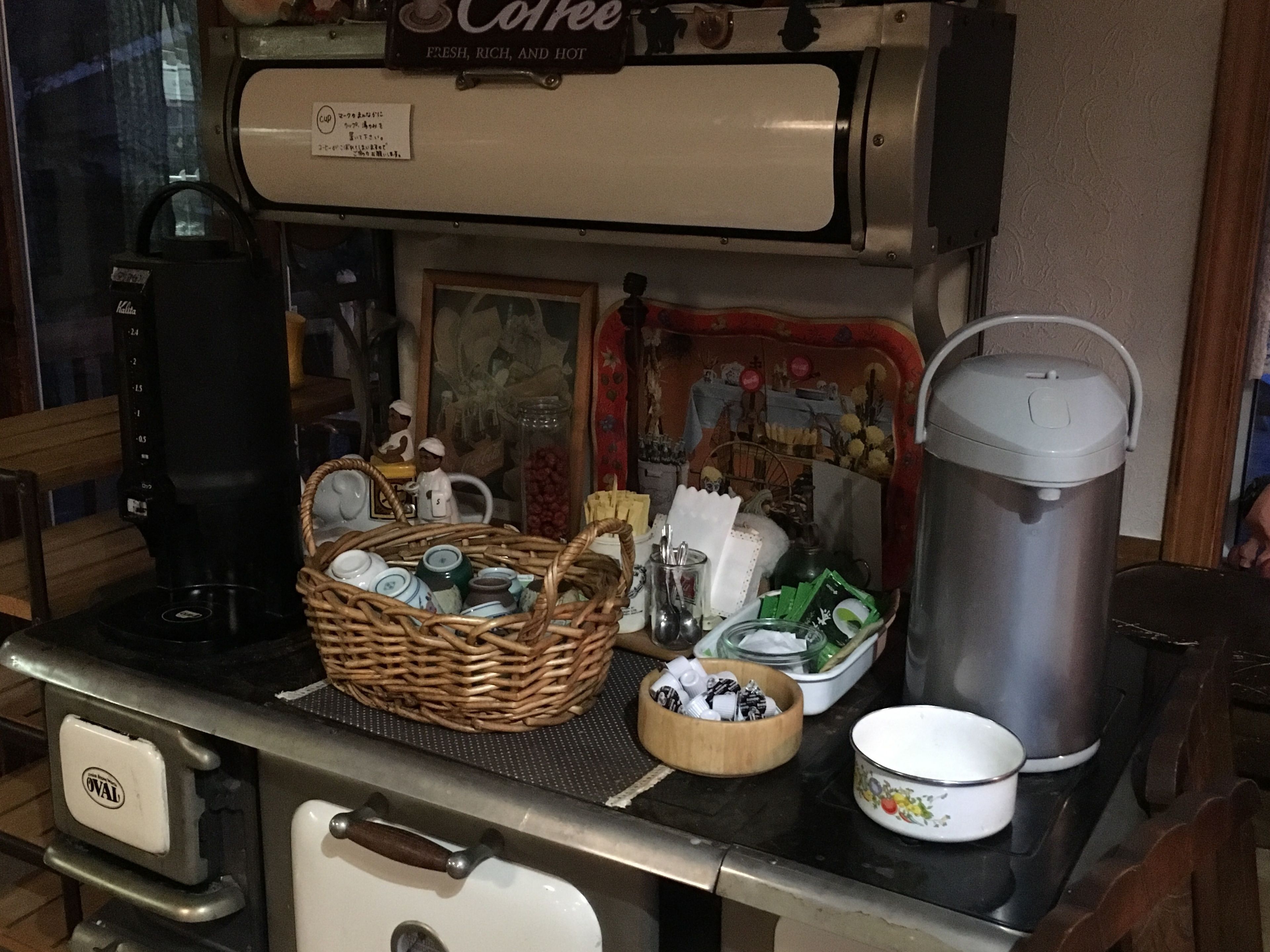 Een kitchenette met een koffiezetapparaat, waterkoker, broodrooster en diverse keukengerei en bakjes.