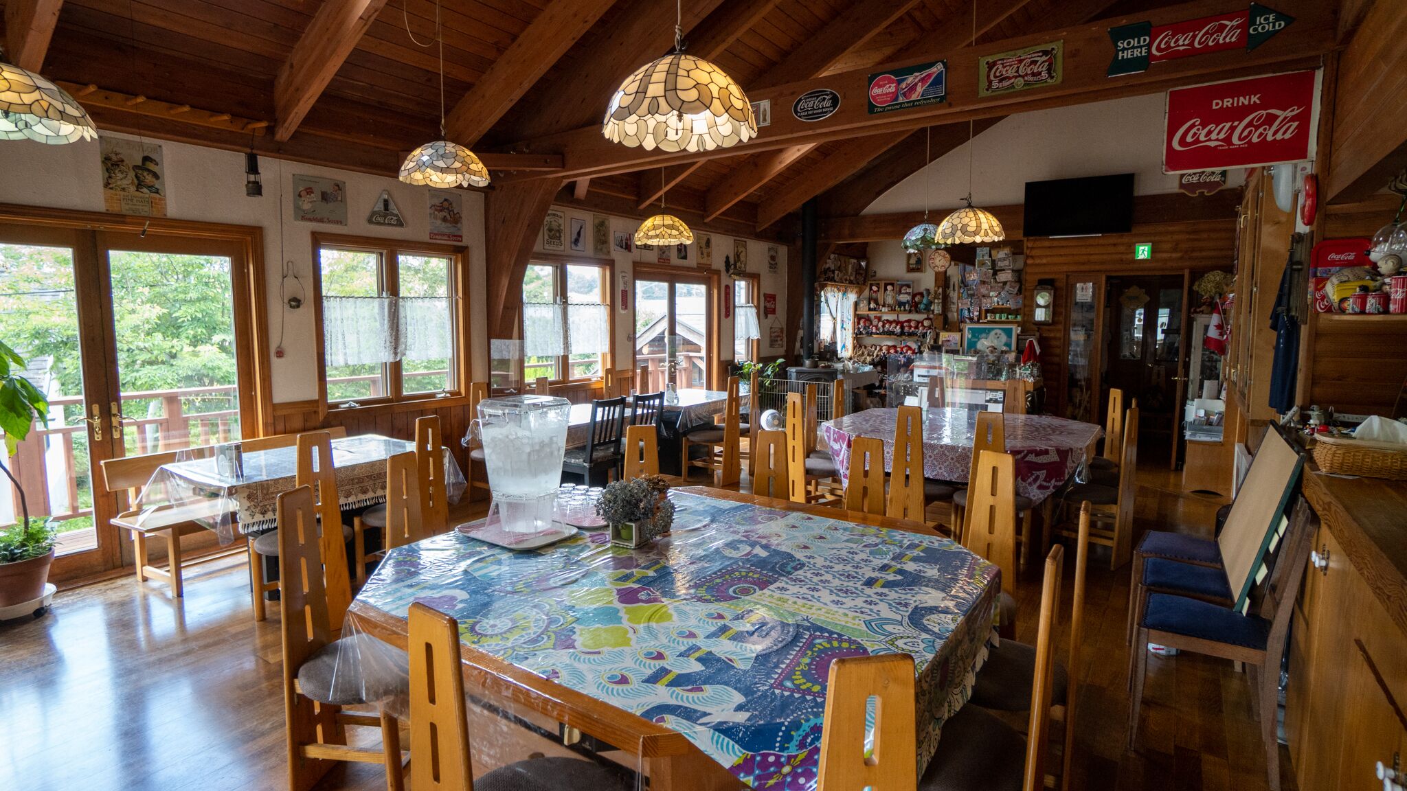 Ein gemütliches Restaurant mit Holzvertäfelung, mehreren Tischen und Stühlen. Coca-Cola-Schilder und ein Hinweis auf eiskalte Getränke sind vorhanden.