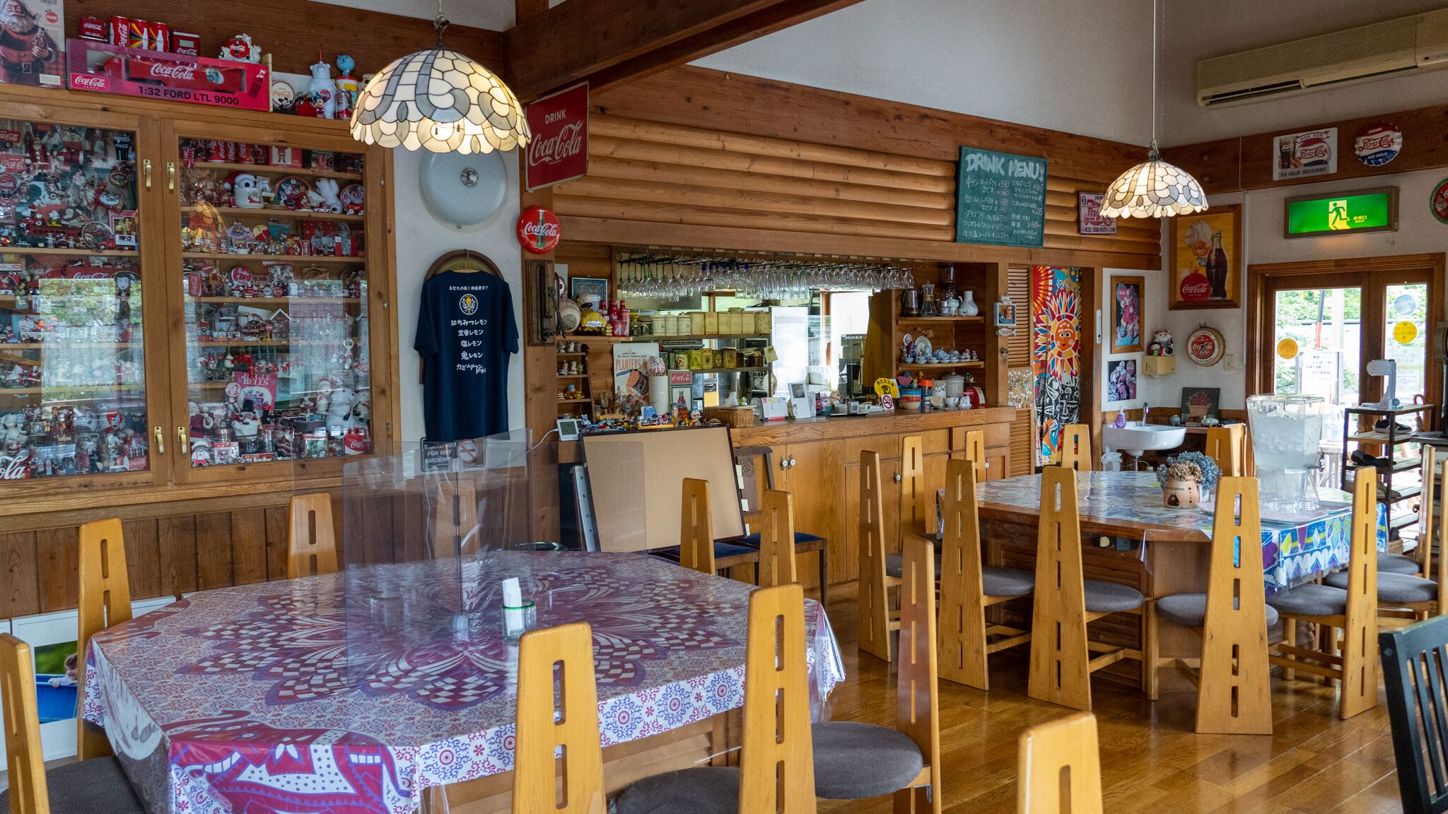 Un accogliente ristorante con interni in legno, un tavolo rotondo con sedie e diversi articoli da collezione Coca-Cola.