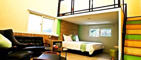 A room with a bed, a sofa, a small table, and a window.