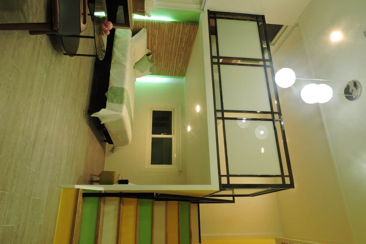Un interior moderno con cama estilo loft, una ventana pequeña y una escalera.