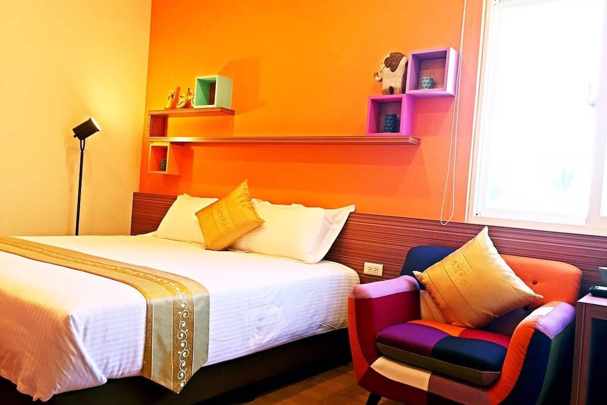 Habitación de hotel con dos camas, una silla y repisas con adornos.