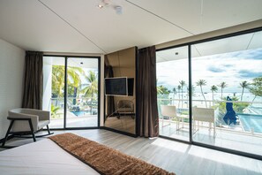 A modern hotel room with a large bed, a flat-screen TV, and a balcony with a pool view.