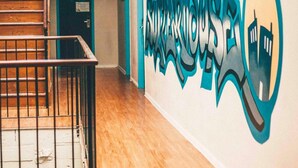 A hallway with a wooden staircase, a wall with graffiti art, and a door labeled "16". - Summer House Brisbane - Hostel (Brisbane)