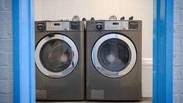 Two front-loading washing machines in a laundry room with a blue door frame.