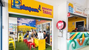 A colorful interior with a yellow counter, red stools, and a mural of a landscape. - Summer House Brisbane - Hostel (Brisbane)