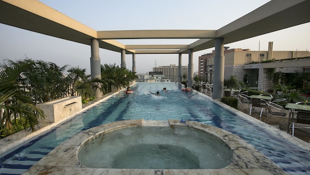 Ein Pool auf dem Dach mit Whirlpool, umgeben von Palmen und Sitzgelegenheiten im Freien.