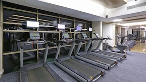 Eine Reihe von Laufbändern in einem Fitnessstudio, mit digitalen Anzeigen.