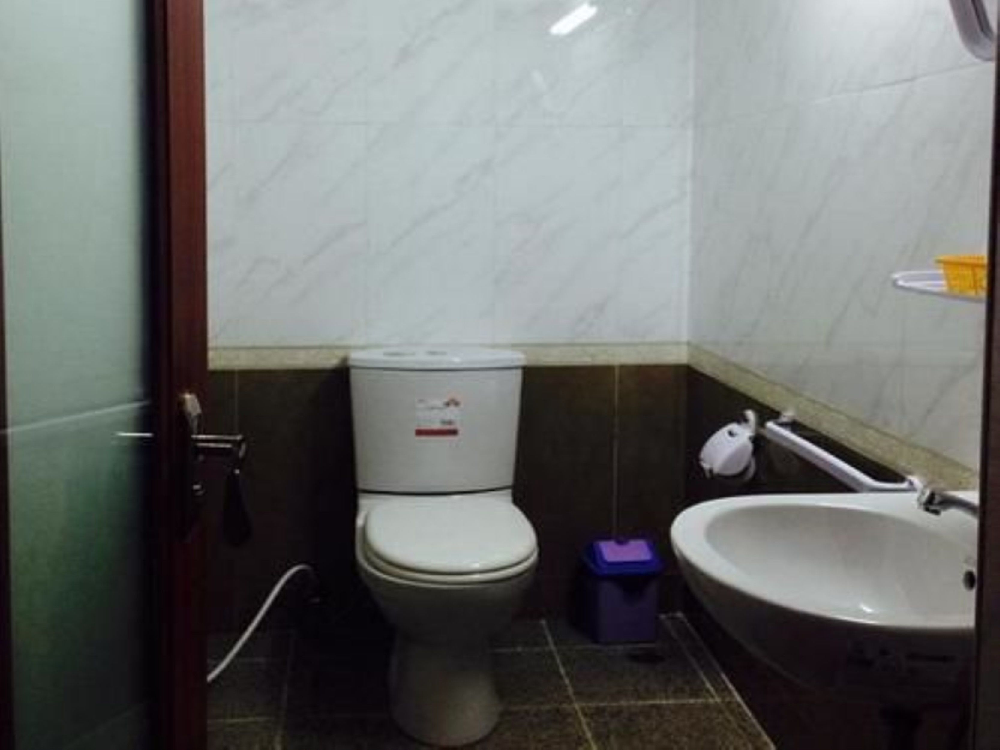 A small bathroom with a toilet, a sink, and a trash bin.