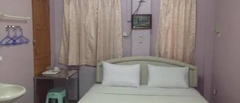 Un dormitorio con cama, mesita de noche, espejo, lavamanos y cortinas.