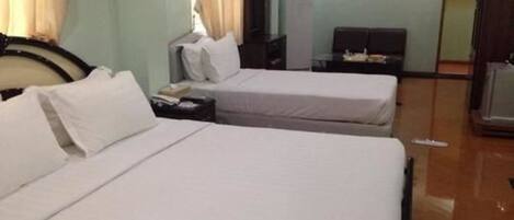 A hotel room with two single beds, a desk with a chair, a wardrobe, and a painting on the wall.