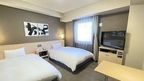 Habitación de hotel con dos camas, un televisor de pantalla plana, un escritorio y una ventana con cortinas.