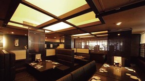Un restaurante con mobiliario de madera oscura, un techo alto con tragaluces y vistas a la ciudad a través de amplias ventanas.