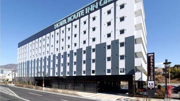 Un hotel de varios pisos con un diseño moderno, que destaca un letrero llamativo del Hotel Route Inn Grand.