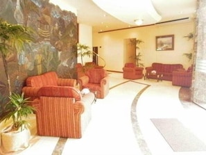 A lobby with sofas, a coffee table, and potted plants.