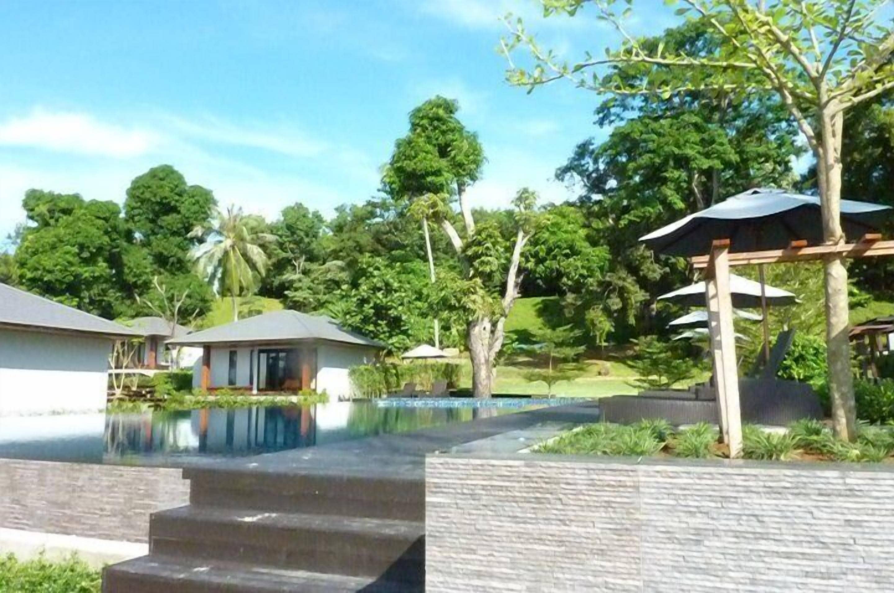 A modern resort with a swimming pool, outdoor seating, and lush greenery.