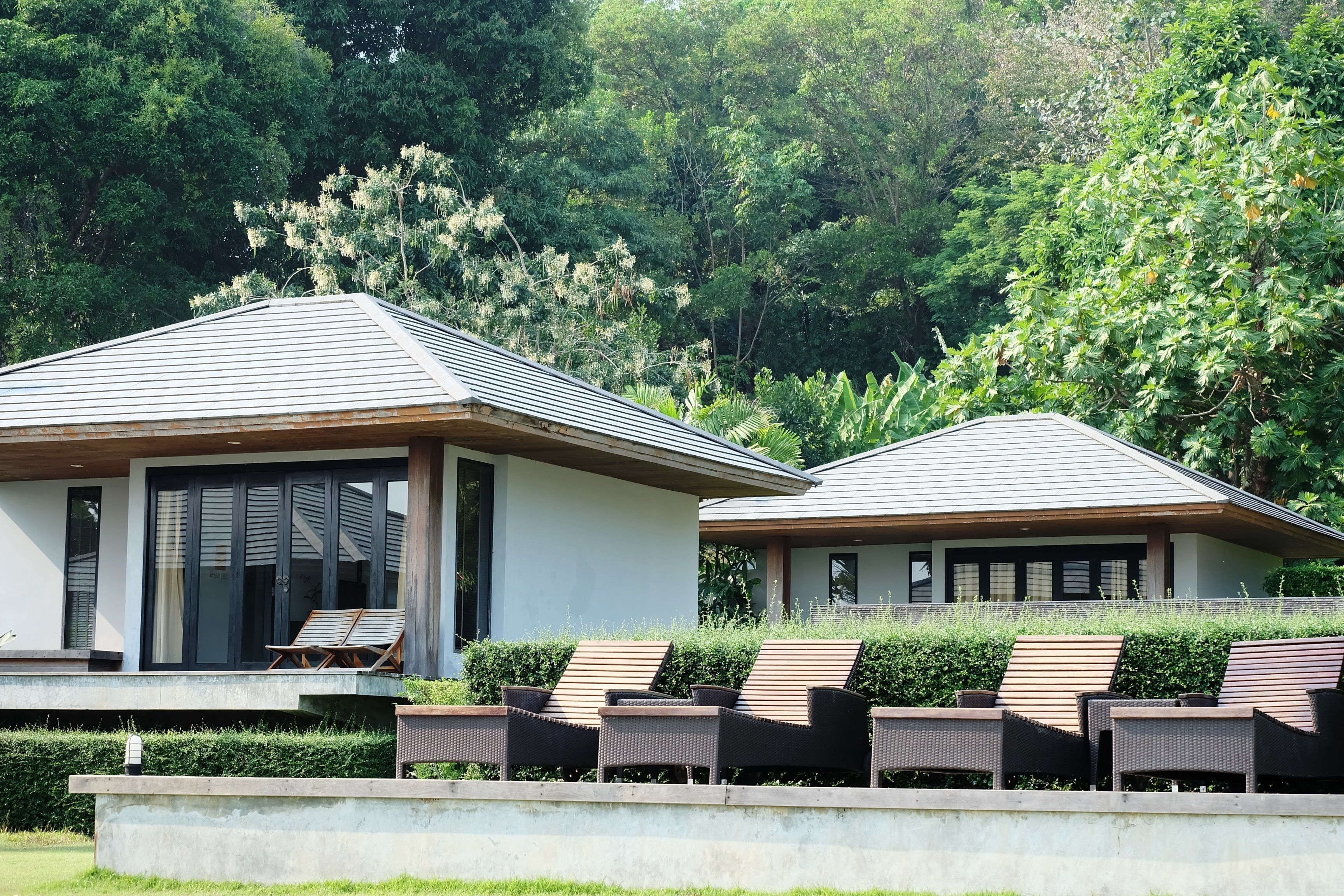 Two modern buildings with large windows and a covered outdoor seating area with lounge chairs.