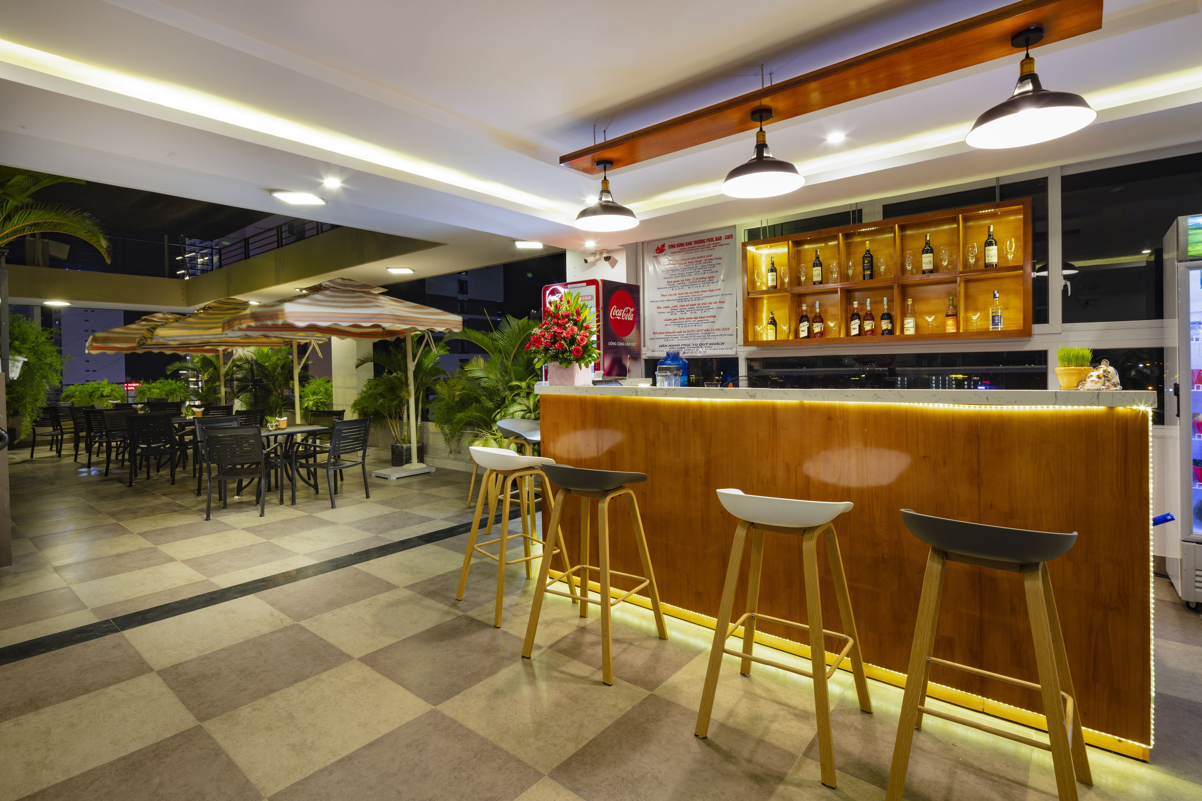 A bar area with a wooden counter, bar stools, and a Coca-Cola sign.