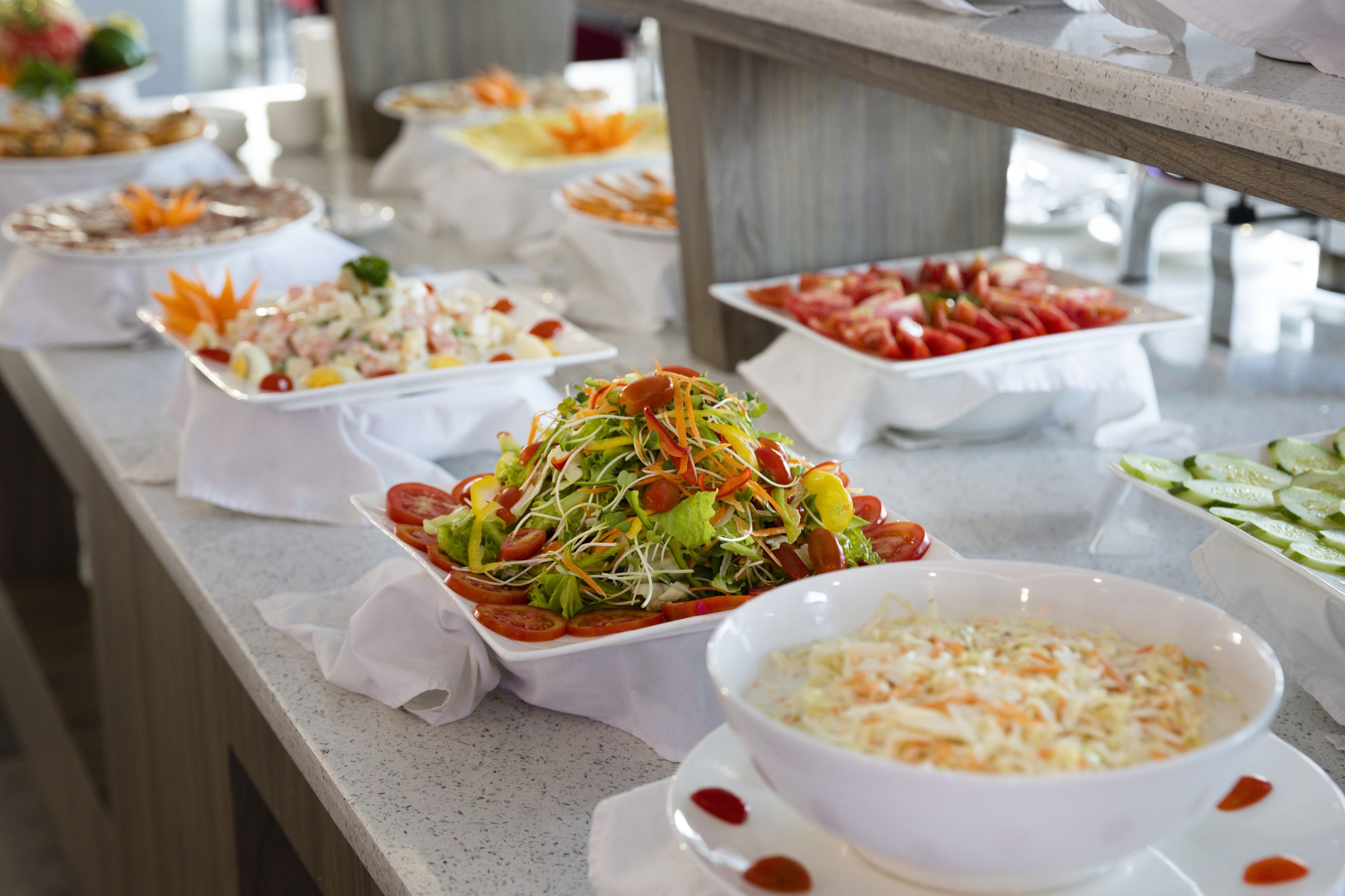 A buffet with various dishes including salads, fruits, and vegetables.