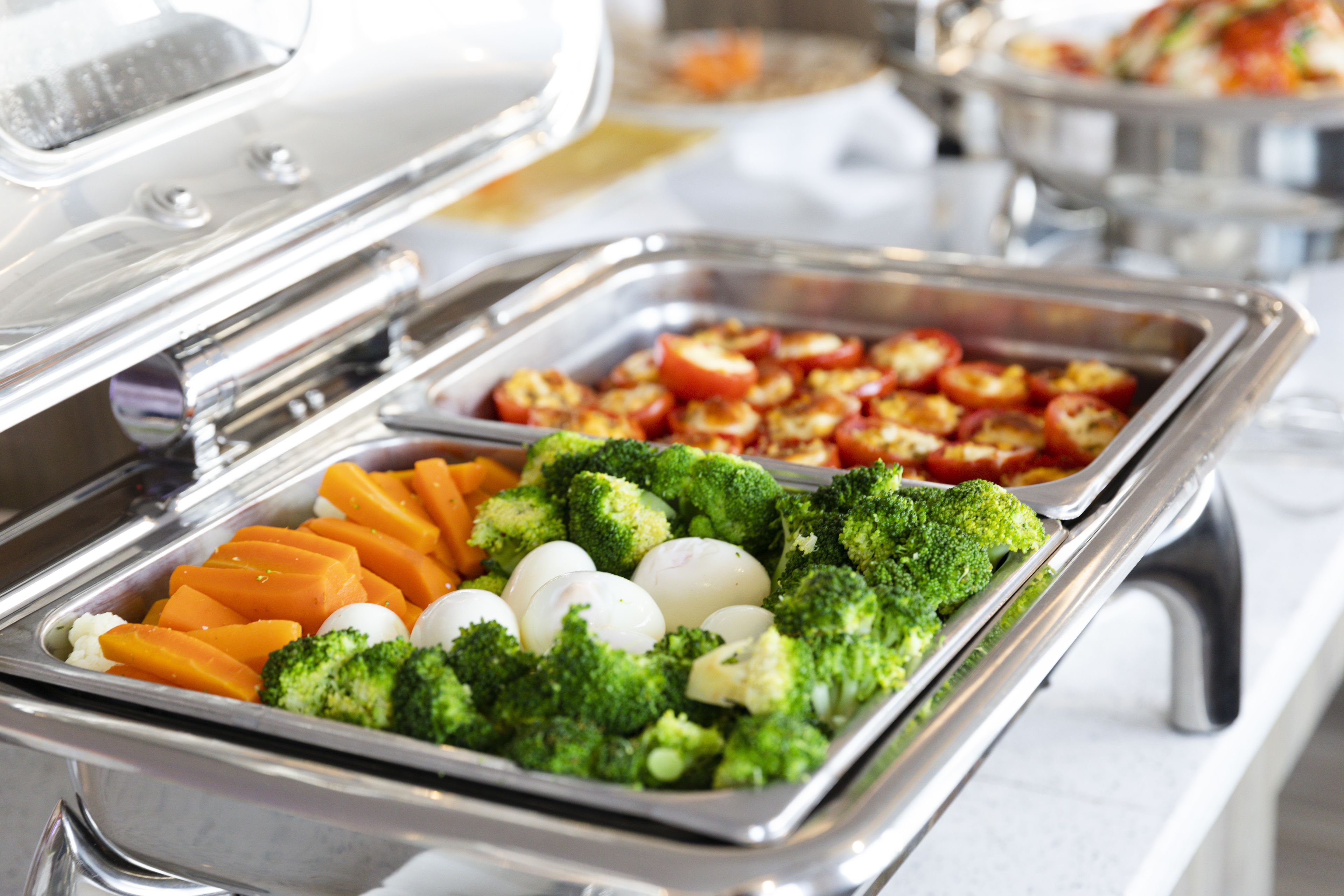 A buffet with various vegetables including broccoli, carrots, and tomatoes.