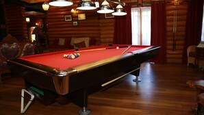 Taula de bitlles en una cabana de fusta amb terres de fusta i làmpades penjants.