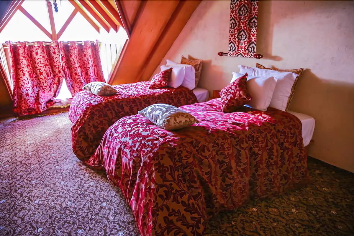 Un dormitorio con dos camas, ropa de cama estampada y una ventana con cortinas.