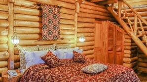 Un dormitori de cabana de fusta amb un llit, parets de fusta, una escala i una làmpada penjant.