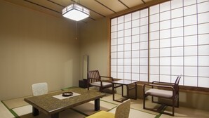 A traditional Japanese room with tatami flooring, a low table, two chairs, and a sliding door. - Hotel Seikoen (Nikko)