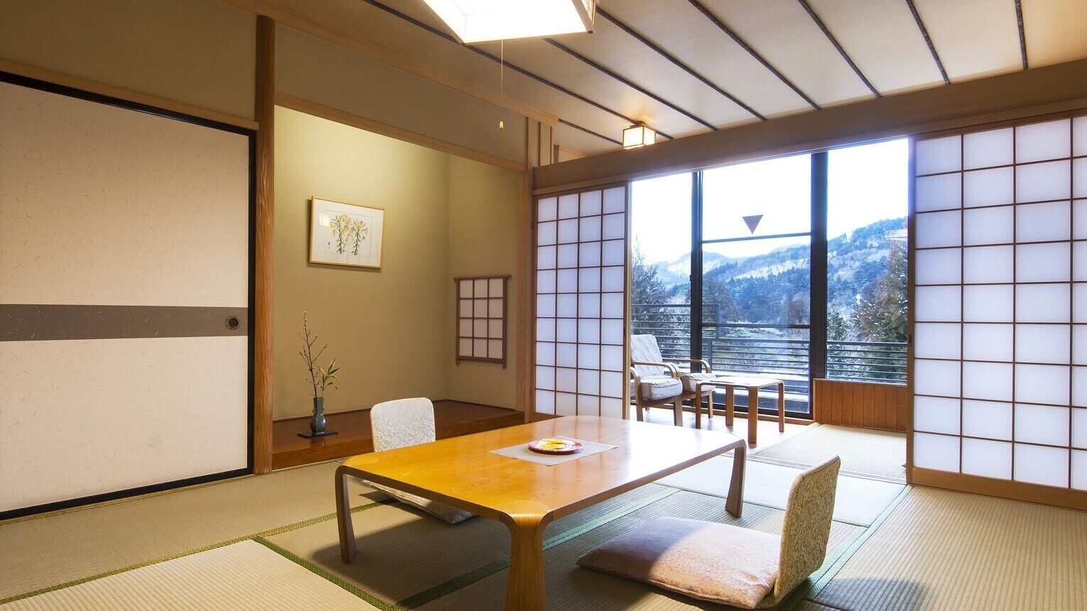 A traditional Japanese room with tatami flooring, a low table, and a view of mountains through shoji screens.