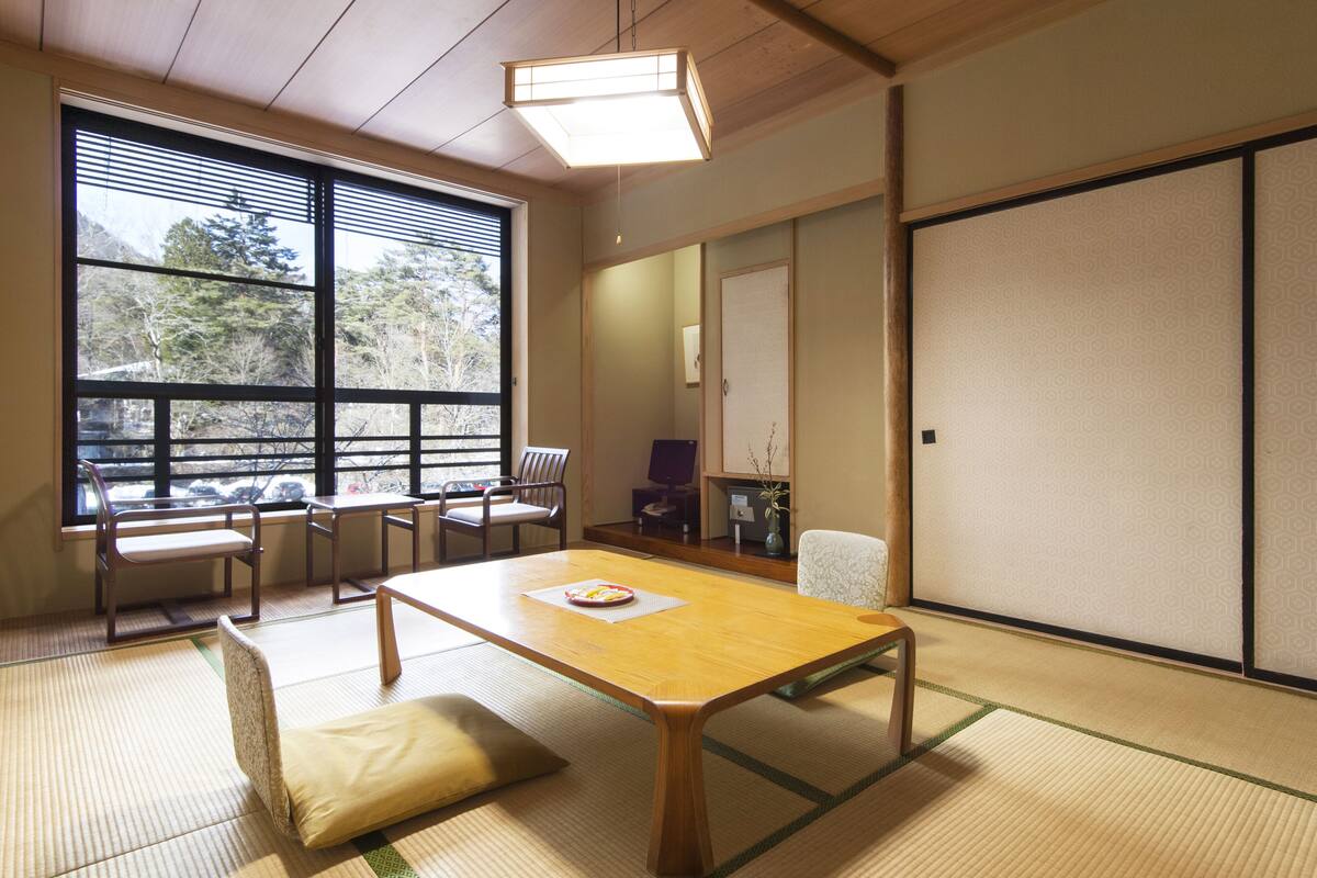 Ein traditioneller japanischer Raum mit Tatami-Boden, einem niedrigen Holztisch und Schiebetüren.