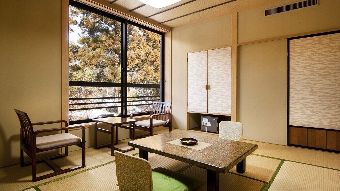 A traditional Japanese room with tatami flooring, a low table, chairs, and sliding doors.