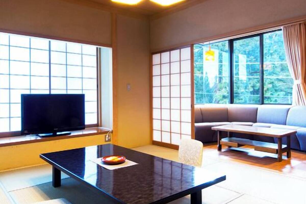 Ein traditioneller japanischer Raum mit Tatami-Böden, einem niedrigen Tisch, einer Couch und verschiebbaren Shoji-Türen.