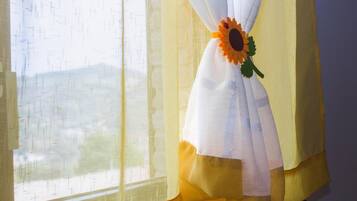 Uma janela com cortinas finas e um objeto decorativo com um girassol.