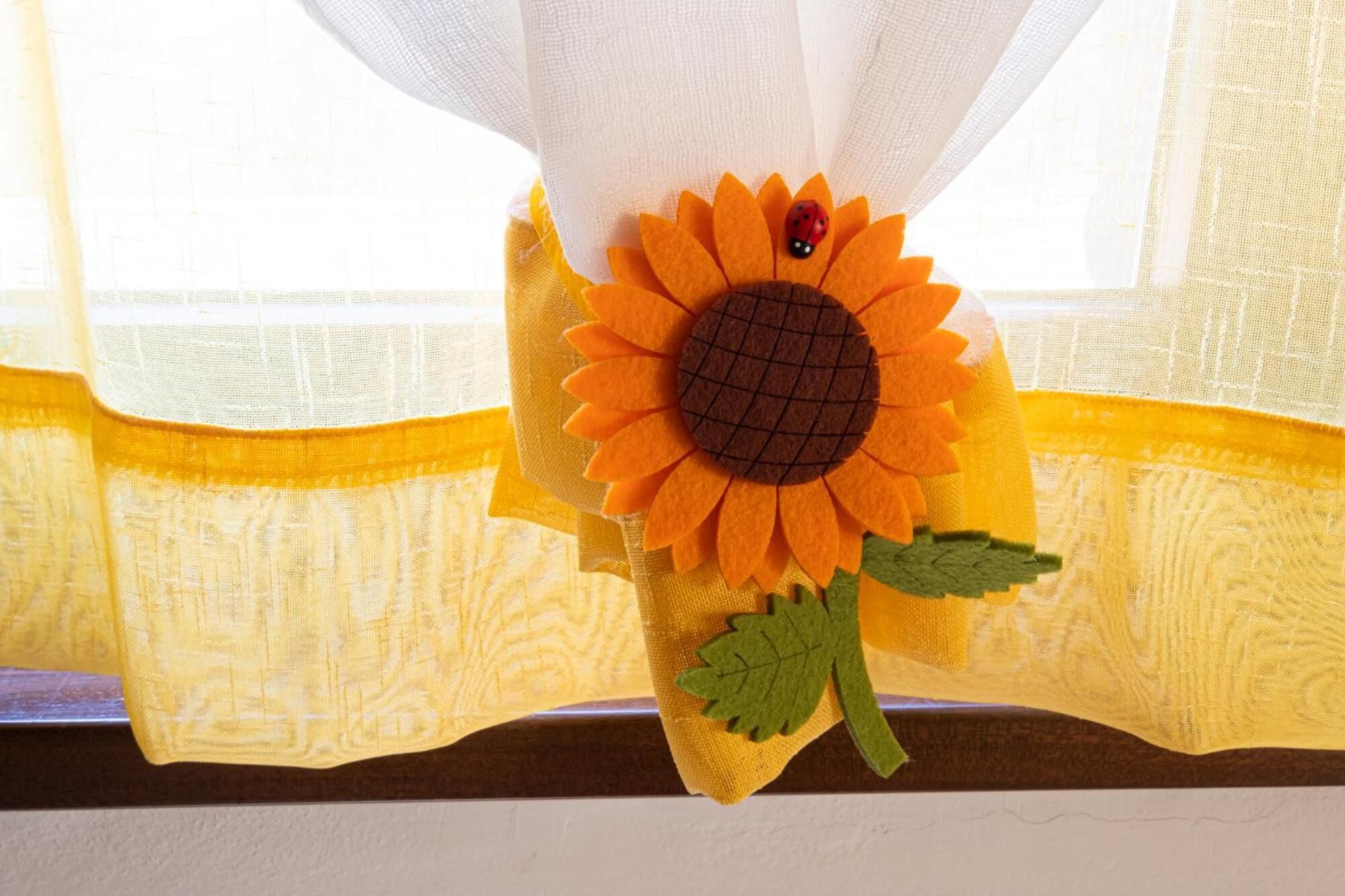 Una decoración de girasol con un escarabajo rojo en el alféizar de una ventana.