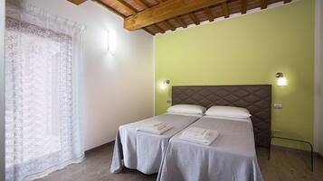 A room with two beds, a wooden ceiling, and a green wall.