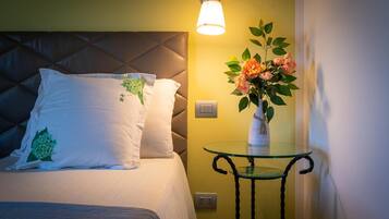 Una habitación de hotel con cama, una mesita de noche con un florero y una lámpara de pared.