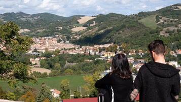 Blick auf eine Stadt von einem erhöhten Aussichtspunkt, mit einer Mischung aus Wohn- und Geschäftsgebäuden, umgeben von grünen Hügeln.