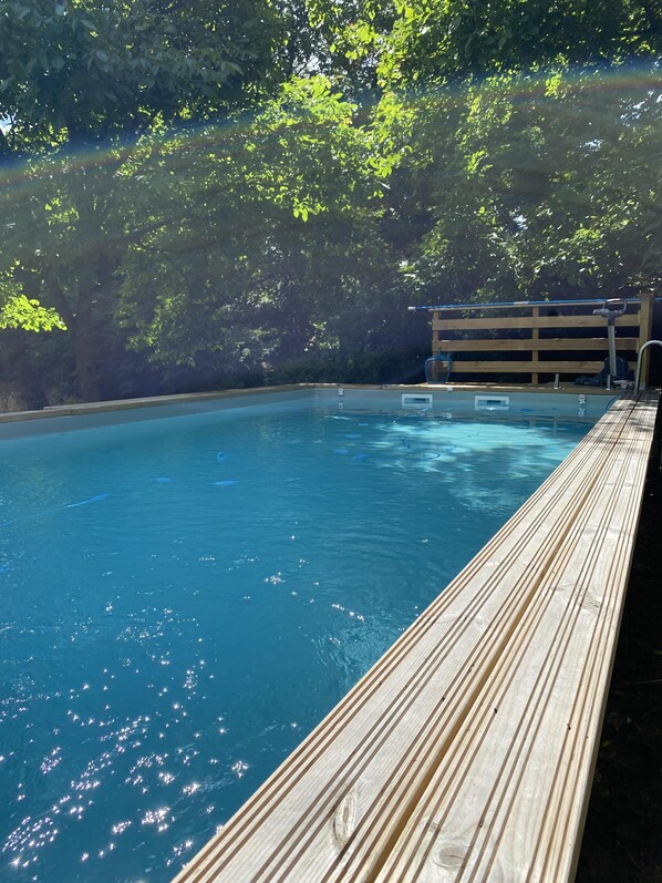 A swimming pool with a wooden deck and a wooden fence in the background.