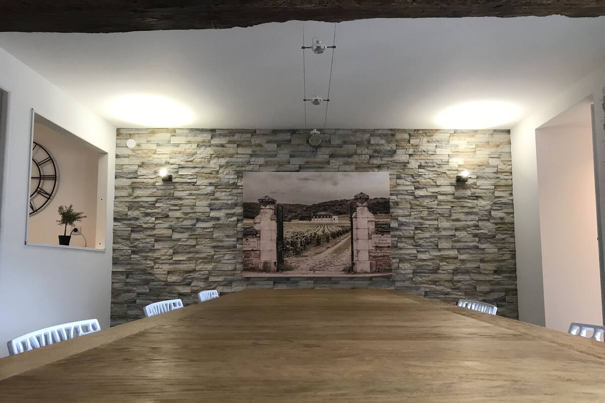 Uma sala de conferências com parede de pedra, uma pintura grande e uma mesa de madeira.