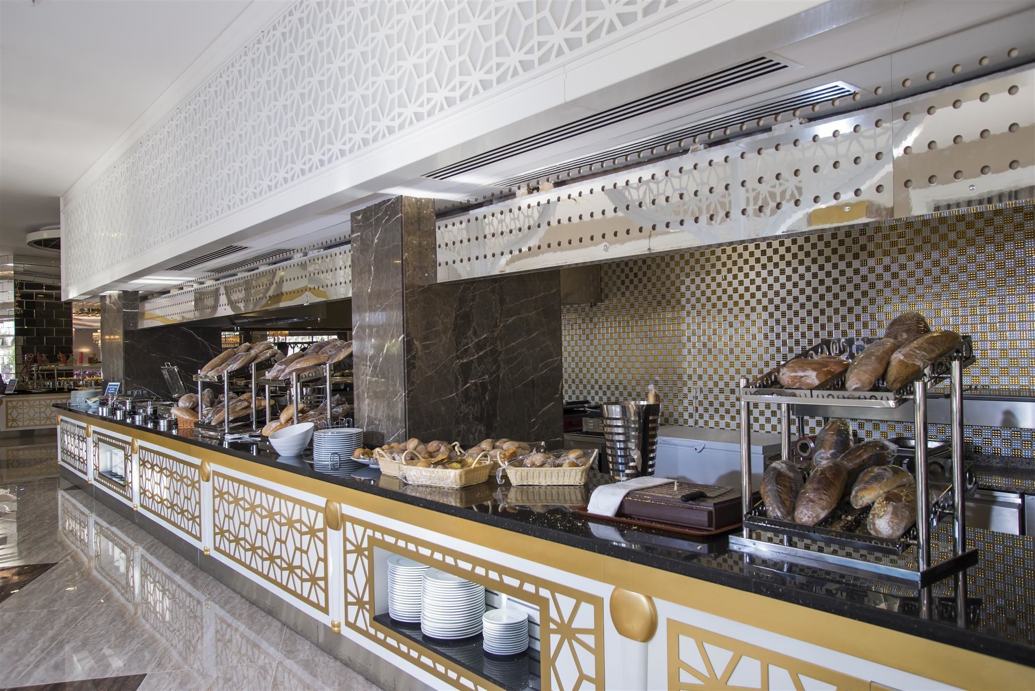 A buffet counter with bread, pastries, and plates.