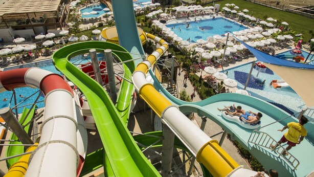 A water park with multiple slides and pools, surrounded by lounge areas with umbrellas. - Dream World Aqua Hotel - All Inclusive (Manavgat)