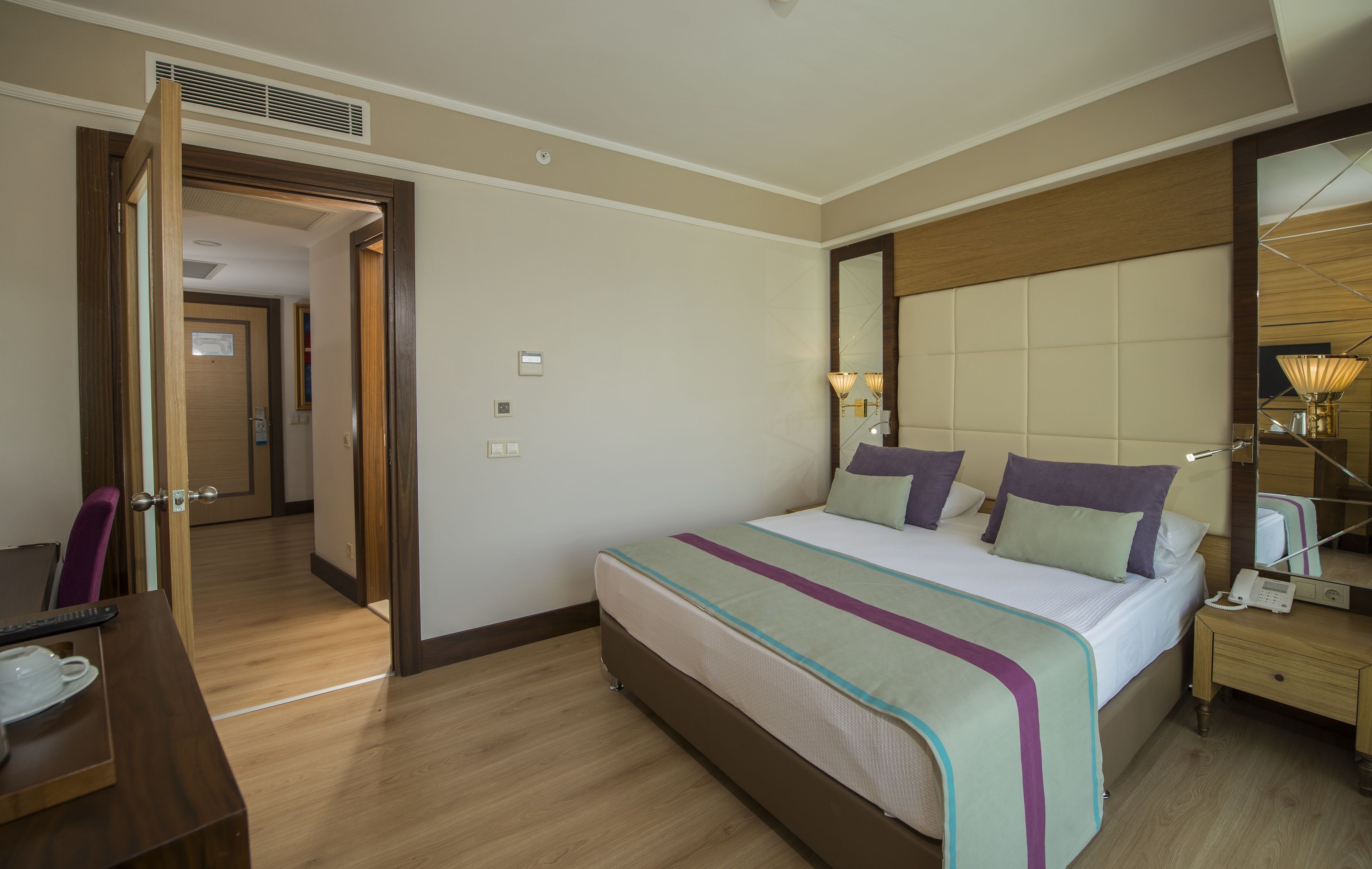 Una habitación de hotel con cama, mesita de noche, lámpara y espejo.