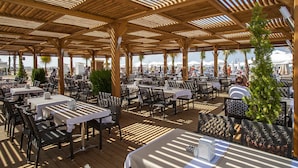 An outdoor dining area with wooden pergolas, tables, and chairs. - Dream World Aqua Hotel - All Inclusive (Manavgat)