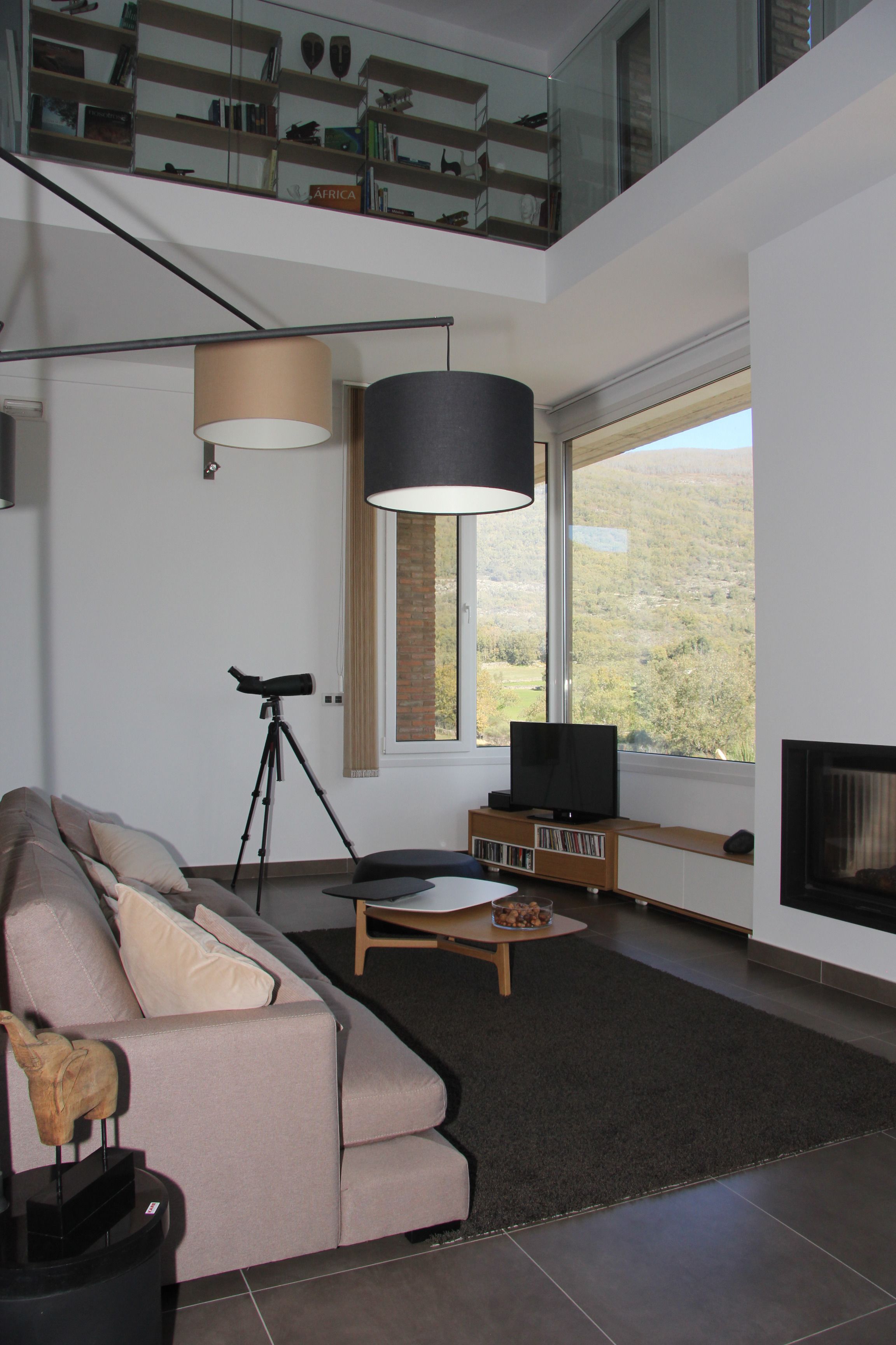 Una sala de estar moderna con un gran ventanal, un telescopio, un televisor de pantalla plana y un sofá acogedor.