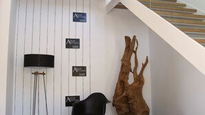 A modern interior with a staircase, a black chair, a wooden sculpture, and signs on the wall. - Agua Antigüa Casa Rural (Garguera)