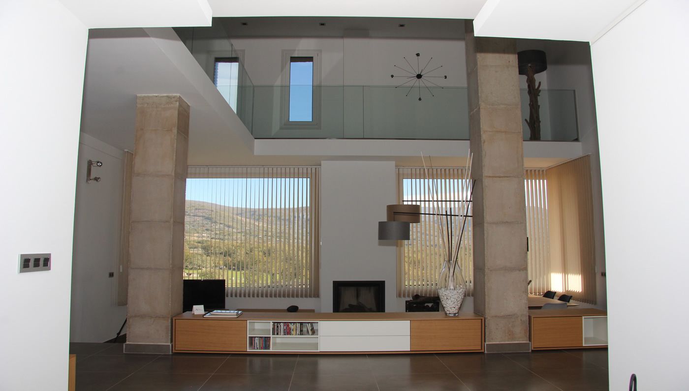 Amplia sala de estar con techo alto, ventanas grandes y chimenea moderna.
