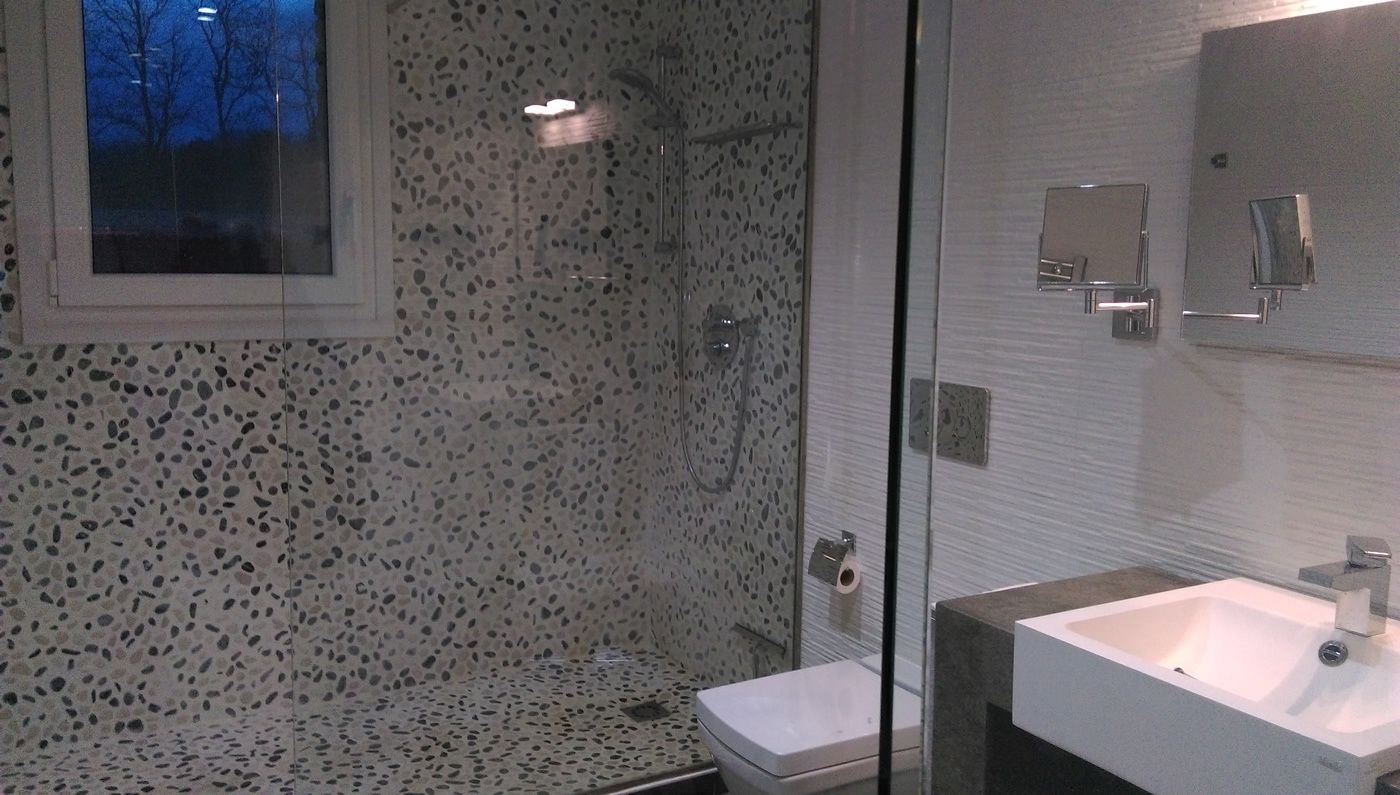 Un baño moderno con cabina de ducha de vidrio, un lavabo blanco y un espejo.